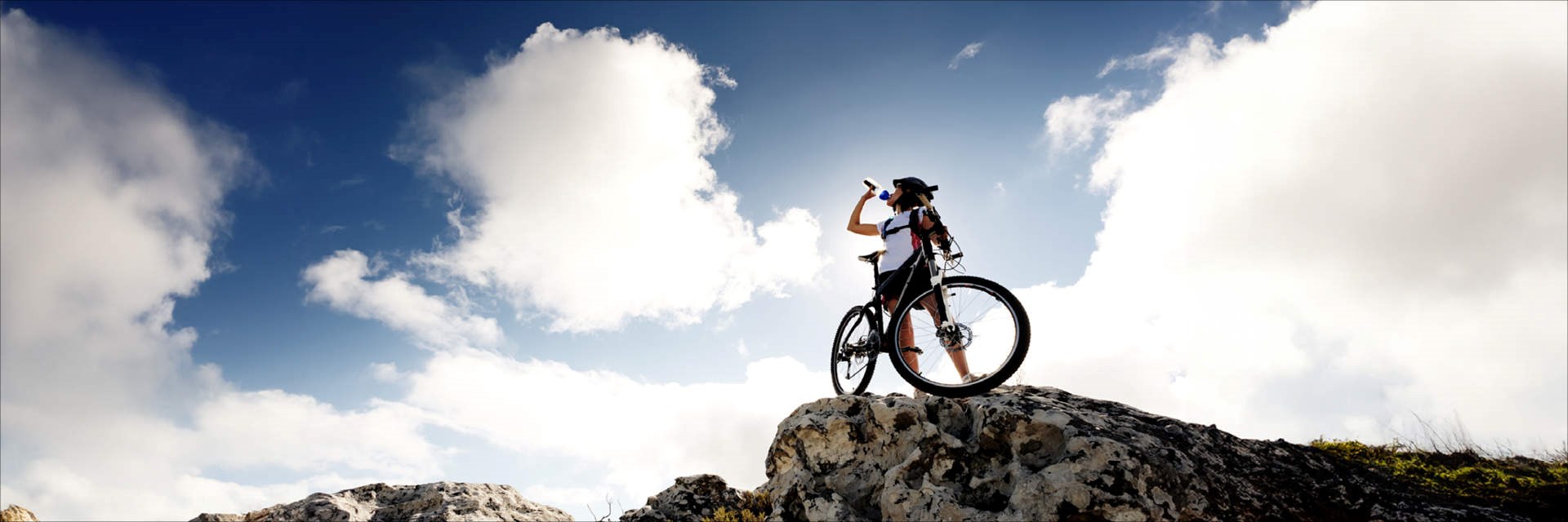 Cyclist on top of a rock drinking