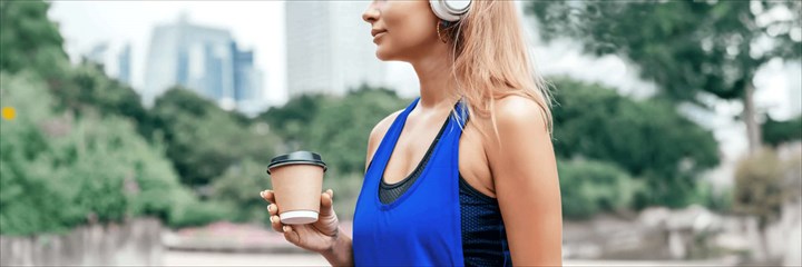 Woman in sports kit holding a coffee