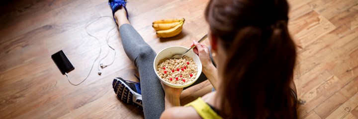 Woman in sports clothing having breakfast on the floor